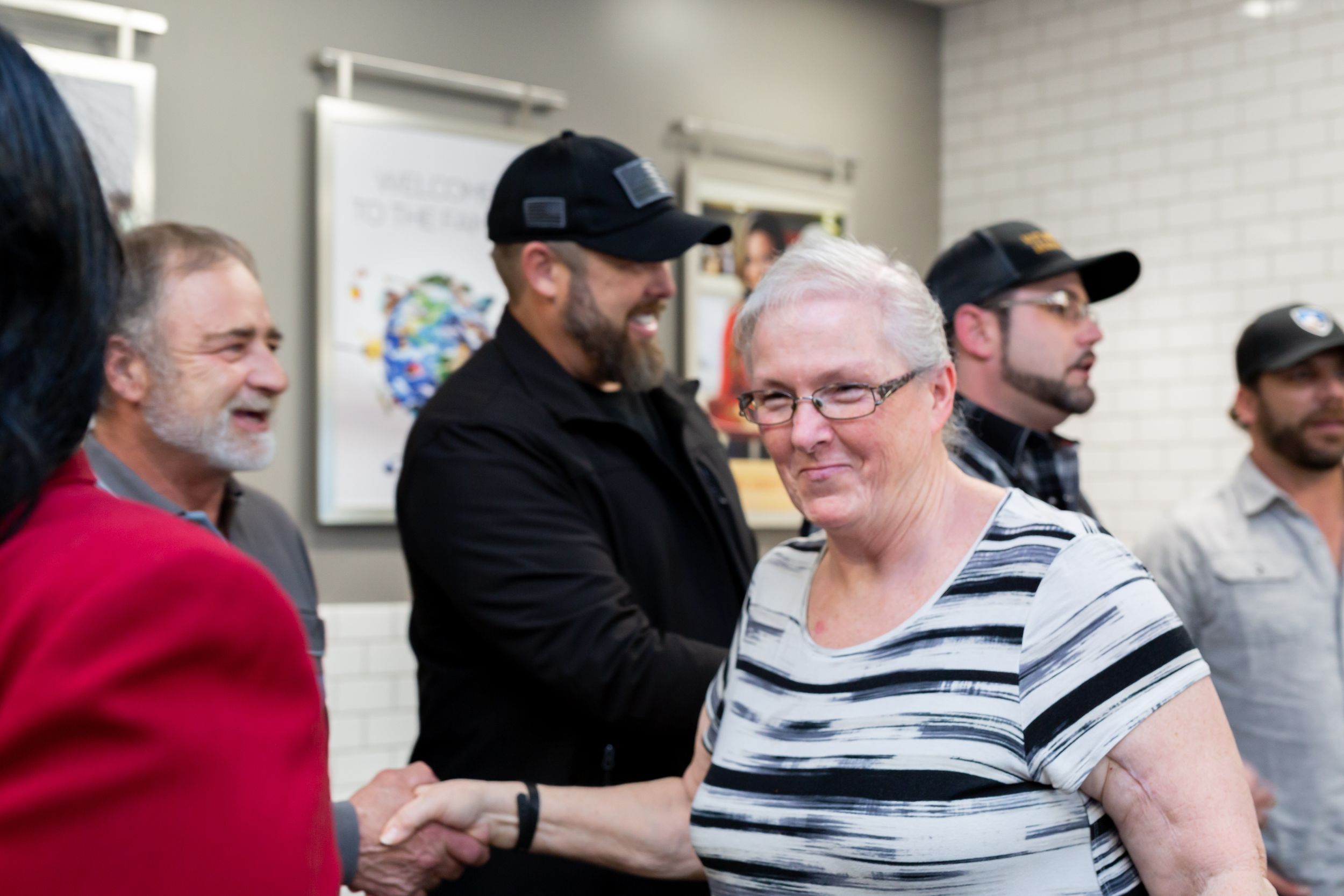 Several people gathered in casual conversation in an indoor office or community space.