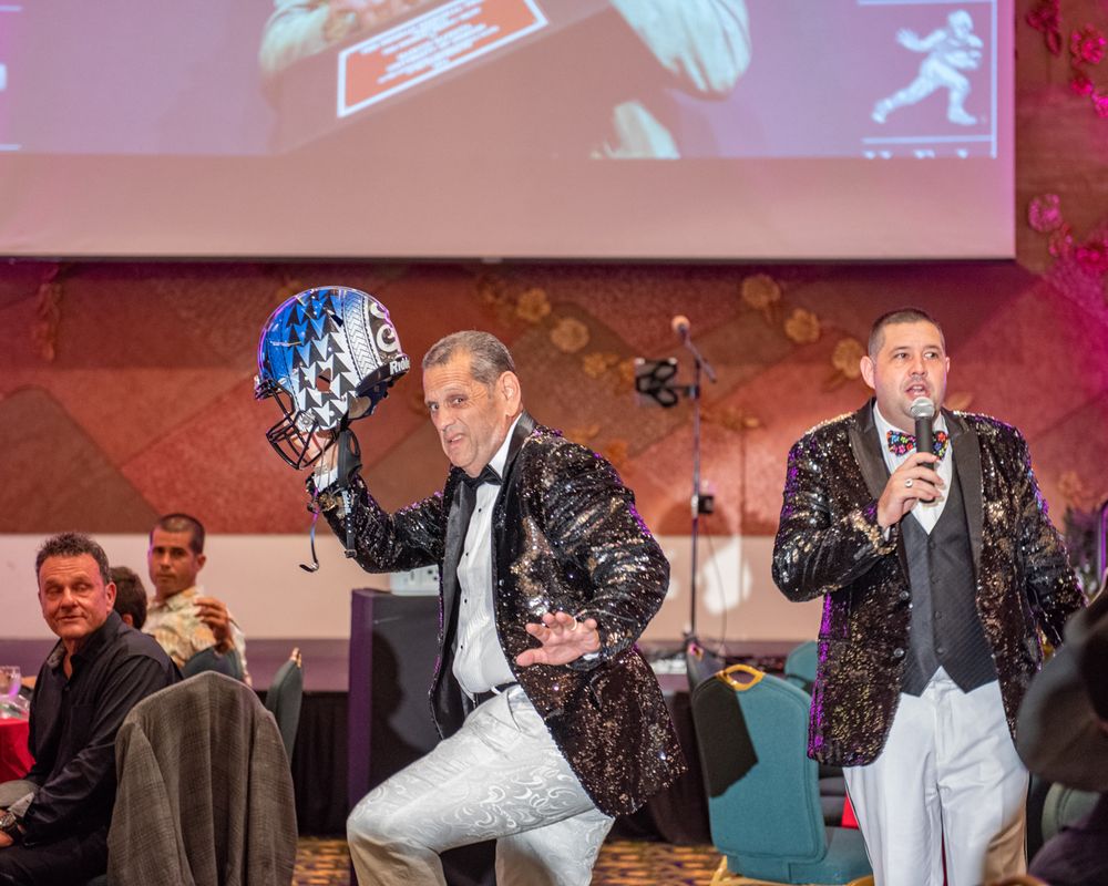 Two performers in sequined jackets entertaining guests during a formal dinner event.