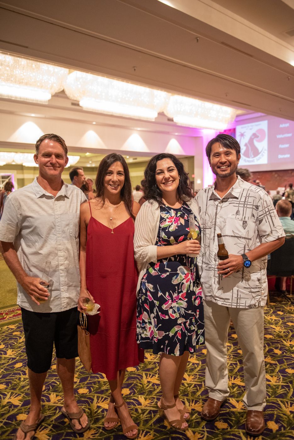 Group of attendees enjoying drinks at formal event in hotel ballroom.