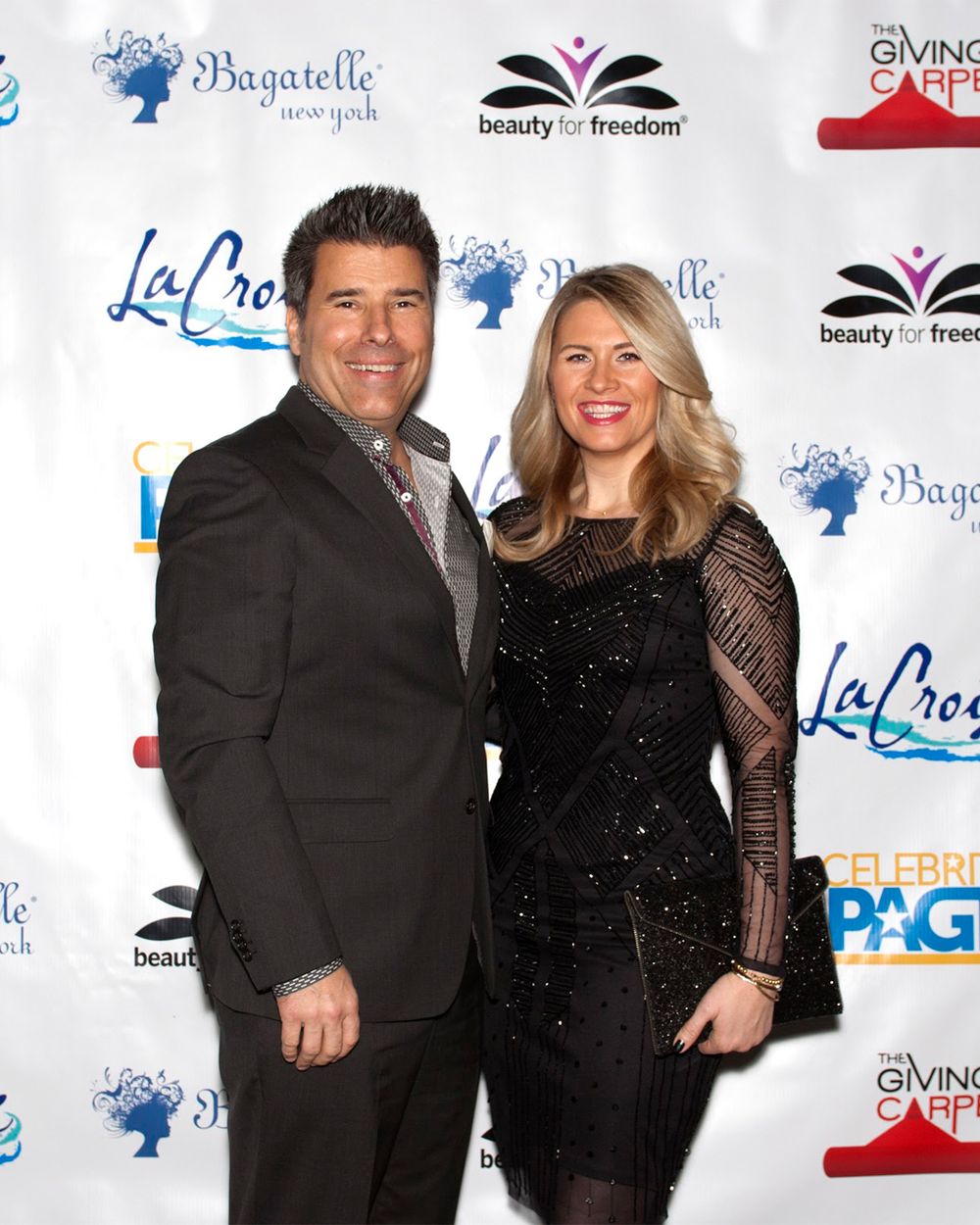 Couple in black formal attire smiling at event with Bagatelle backdrop.