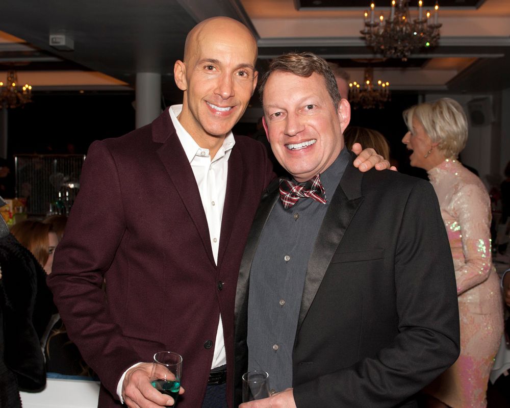 Two men in formal attire, one in burgundy jacket and one in dark suit with bowtie, at indoor event.