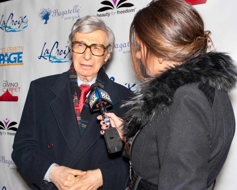 An interview takes place with a person in glasses and formal attire being questioned by someone with a microphone.