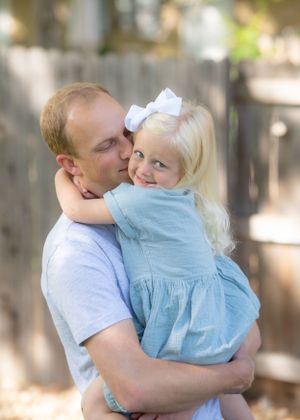 Young father embraces his daughter in their backyard.