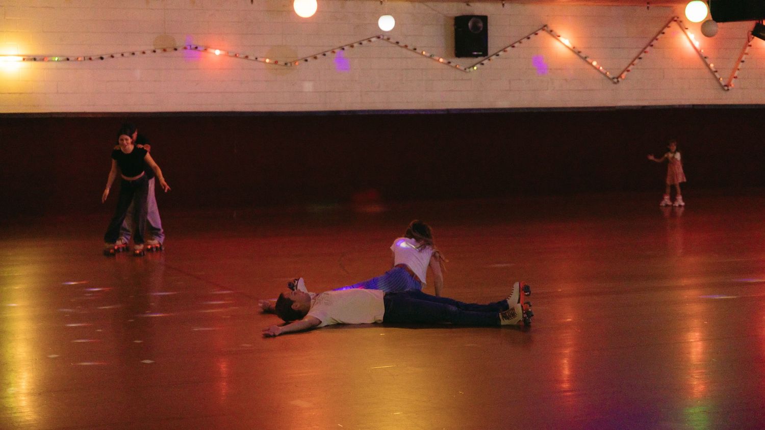 Dancers perform on a dimly lit dance floor with red accent lighting and string lights overhead during a performance.
