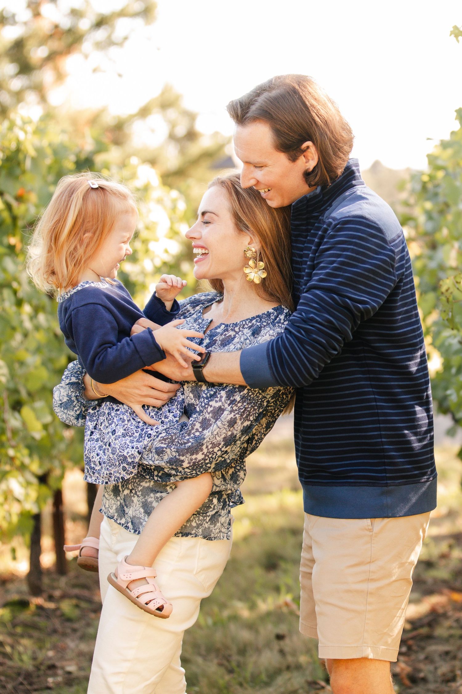 A joyful family moment outdoors with matching blue outfits during golden hour in a natural setting.