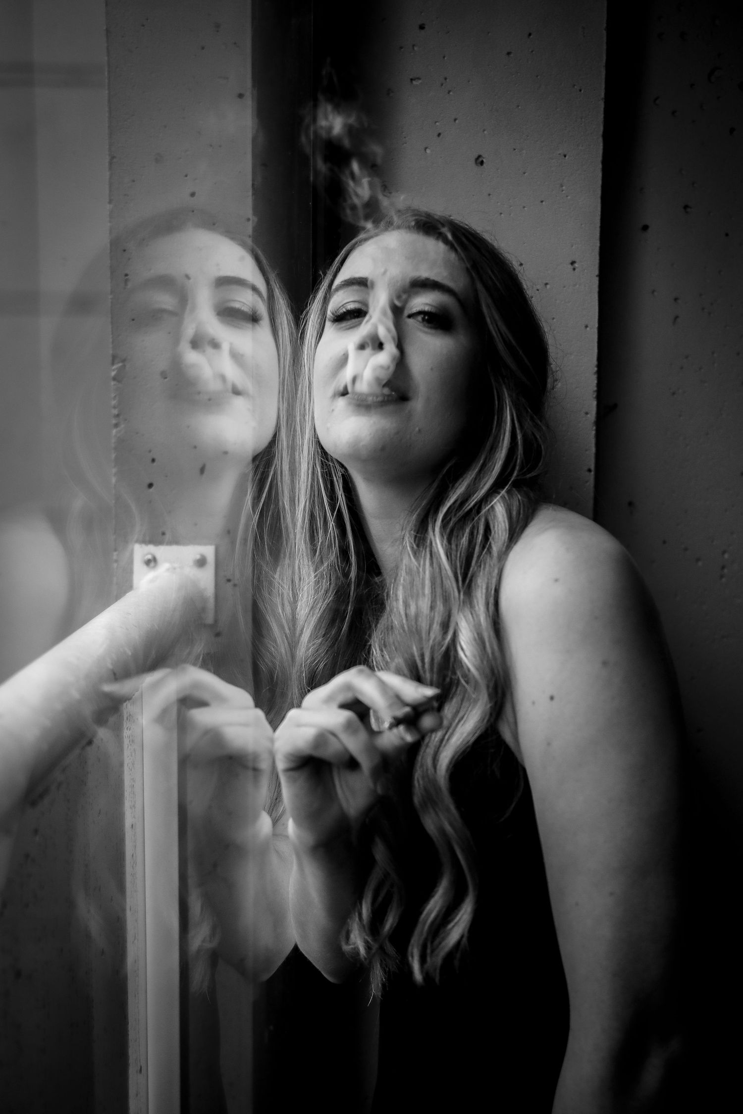 Artistic black and white portrait with smoke effect showing reflection in mirror.