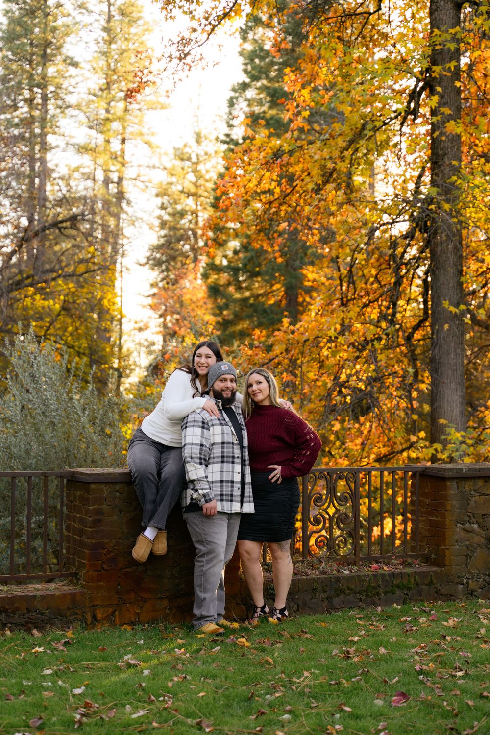 Autumn family photoshoot with fall foliage and wooden fence backdrop.