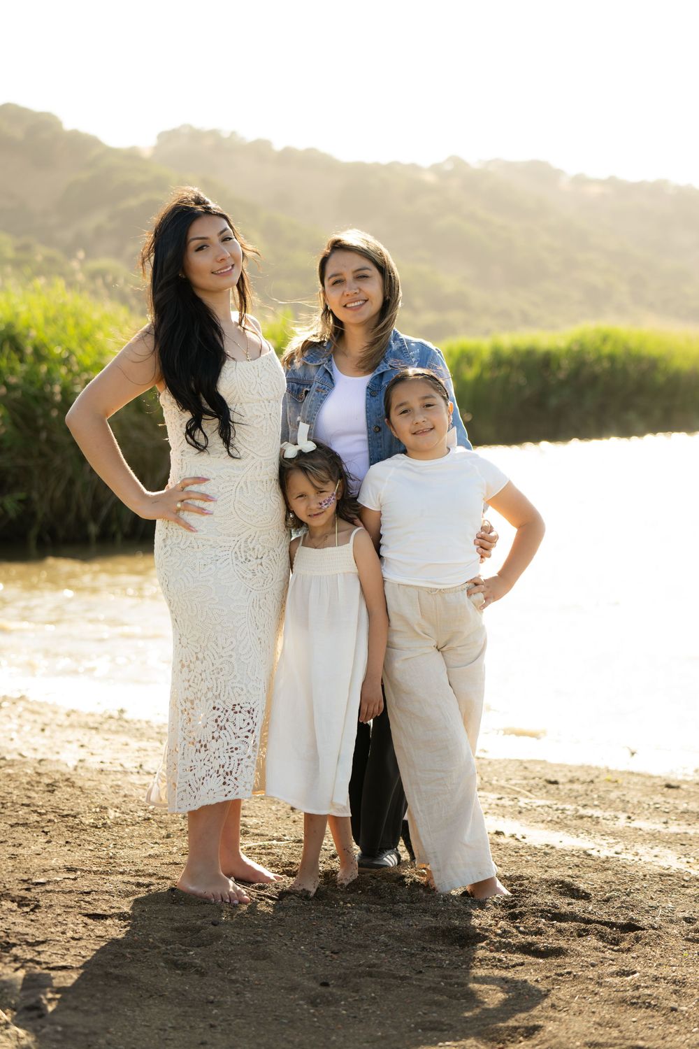 Candid family beach portraits with coordinated white and cream outfits during golden hour.