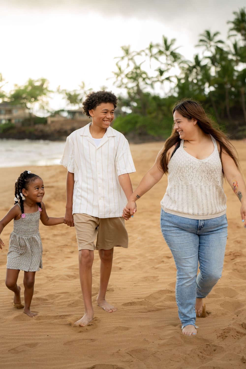 Candid moments of a family walking together on a sandy beach at sunset.