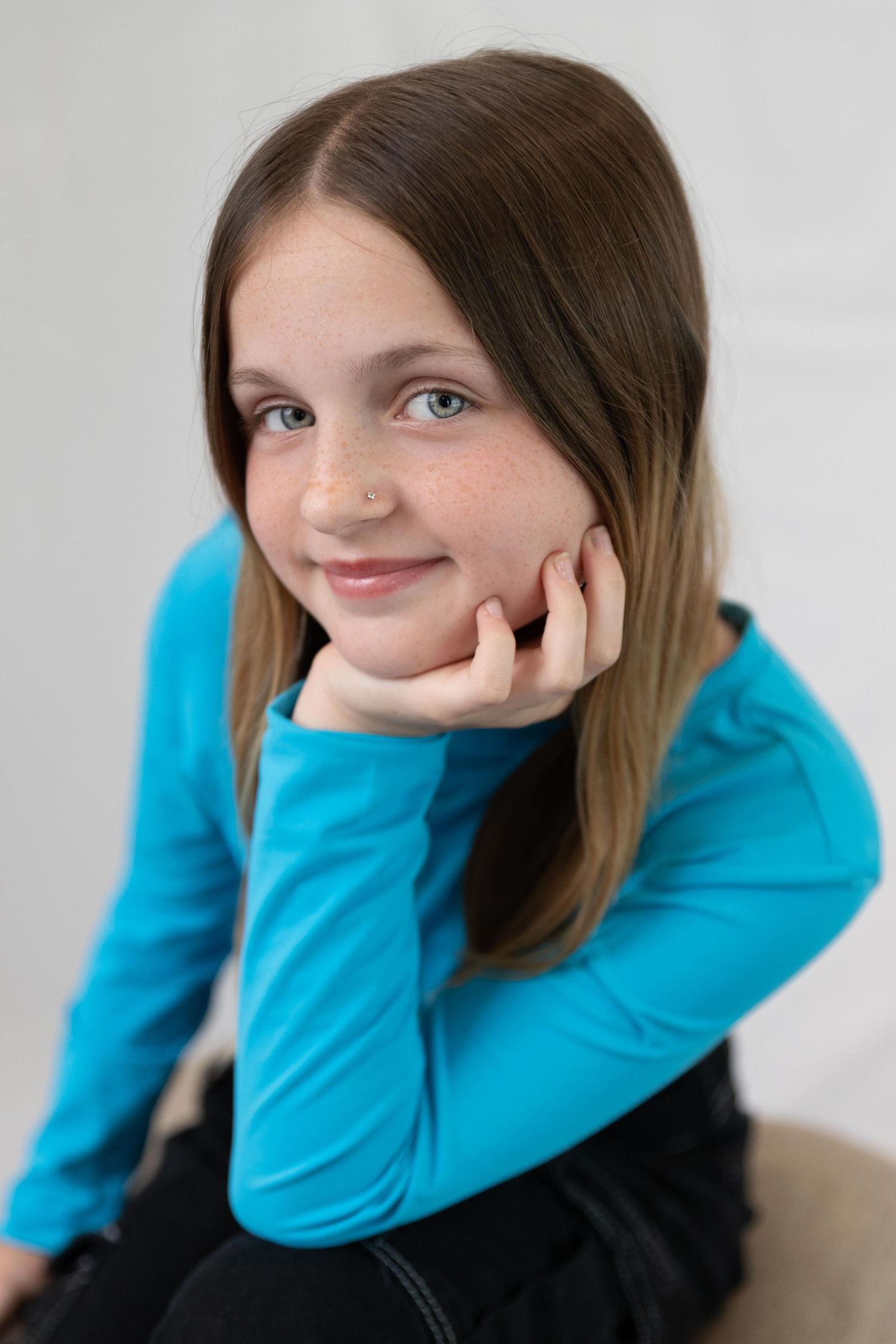 A person in a bright turquoise sweater poses playfully in a series of casual portrait shots against a light background.