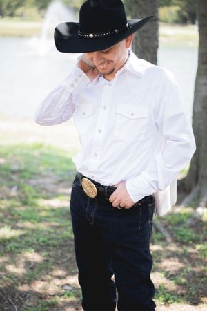 Western style wedding attire featuring white shirt, black pants and cowboy hat details.