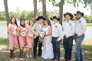 Wedding party in pink dresses and western wear poses together by lakeside.