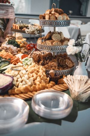 Elegant wedding reception food display with breads, cheeses, and appetizers on tiered stands.