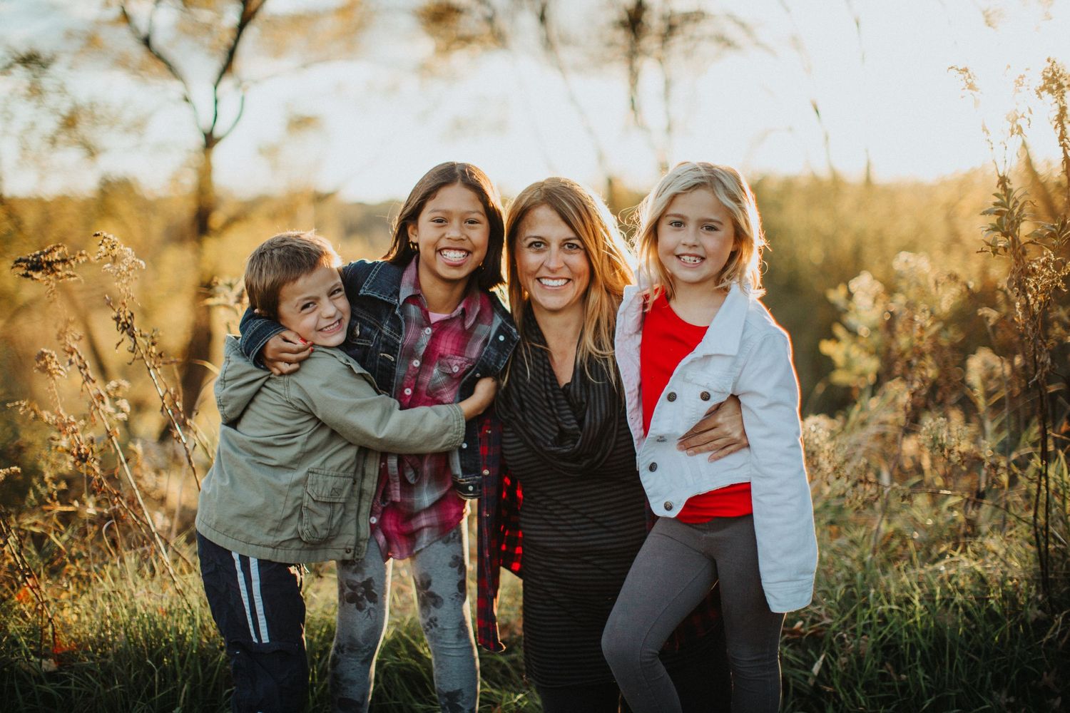 A group of people share joyful moments together in a golden field during sunset.