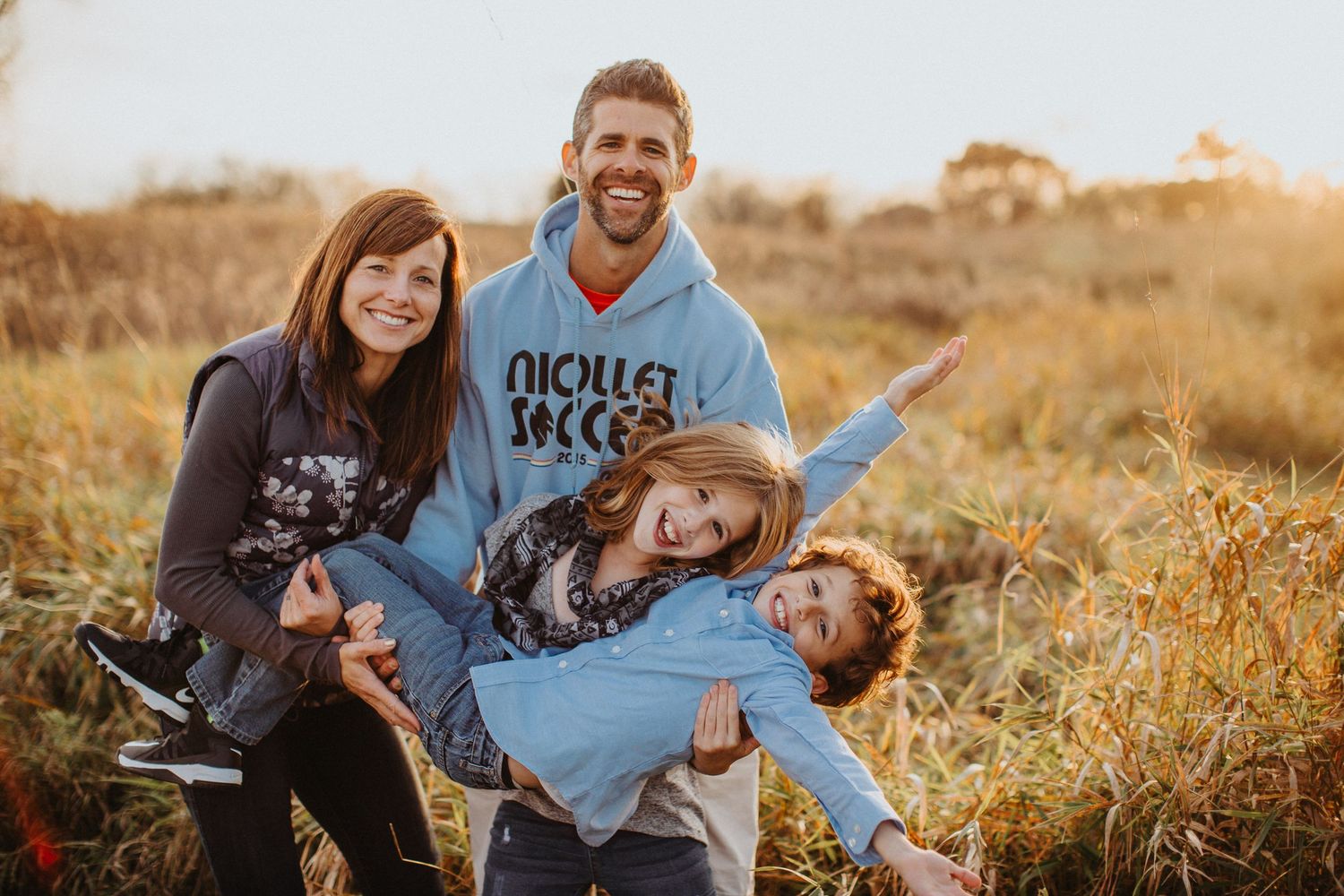 A couple shares joyful moments in a golden field during sunset, creating a warm and romantic atmosphere.