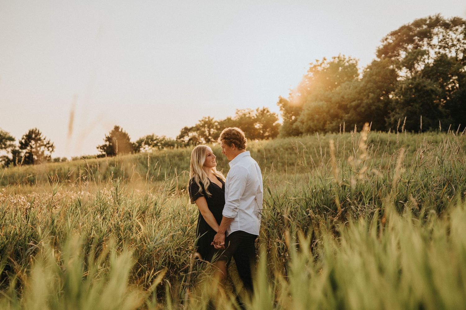 A couple embraces in a golden wheat field during sunset creating a romantic silhouette against the warm light.