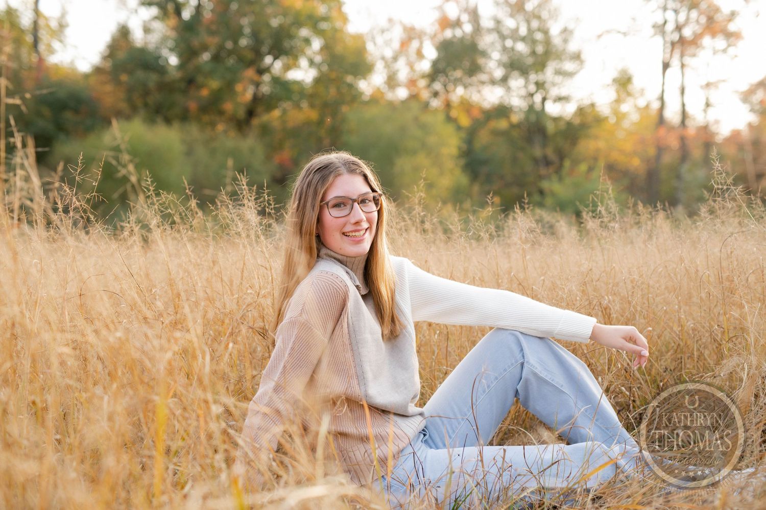 Candid outdoor portrait sitting in tall golden grass during sunset.