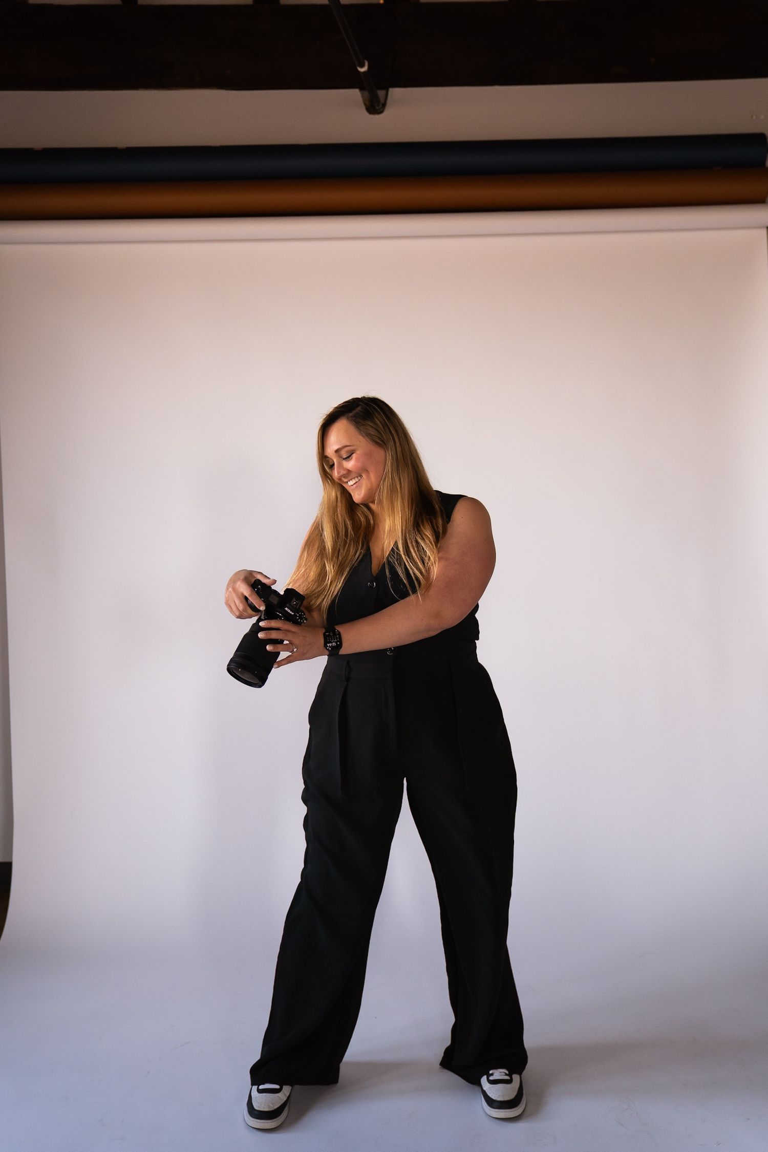 Professional photographer in casual attire posing with camera against white background.