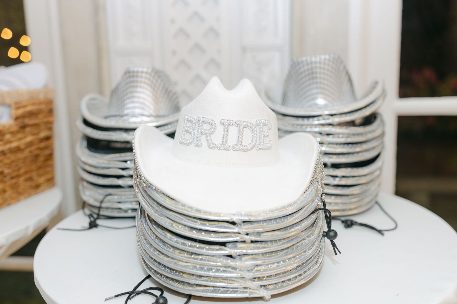 Stacked white cowboy hats with silver glitter trim and a Bride hat on top for a bachelorette party.