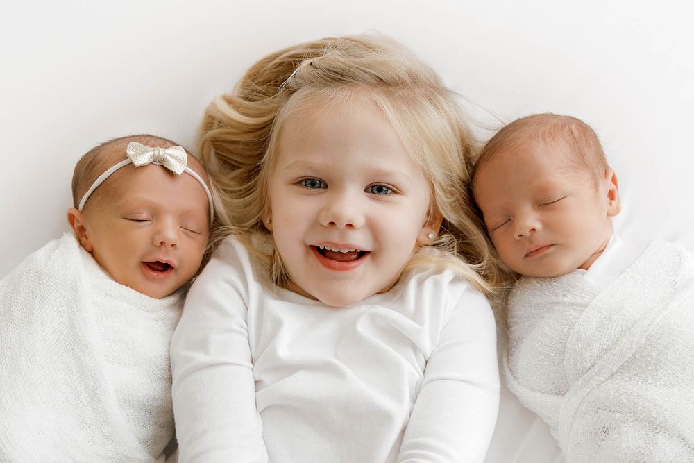 Smiling toddler girl with twin siblings by Temecula newborn twins photographer.