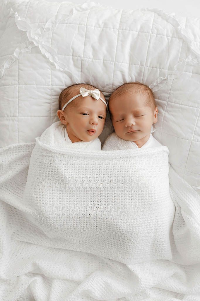 Two newborn twins swaddled in white blanket lying together by Temecula newborn twins photographer.