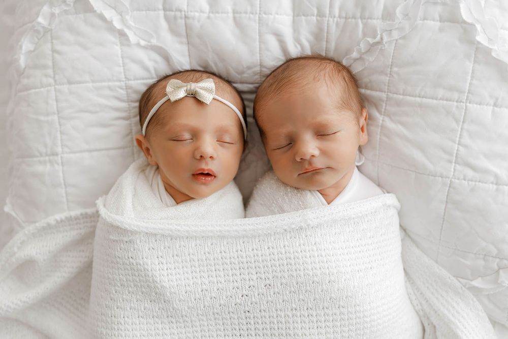 Two sleeping newborn twins swaddled in white blankets, by Temecula newborn twins photographer.