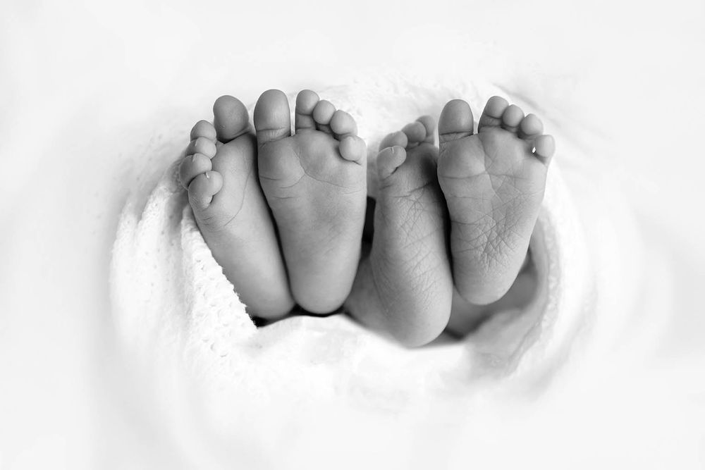 Black and white close-up of two newborn babies tiny feet by Temecula newborn twins photographer.