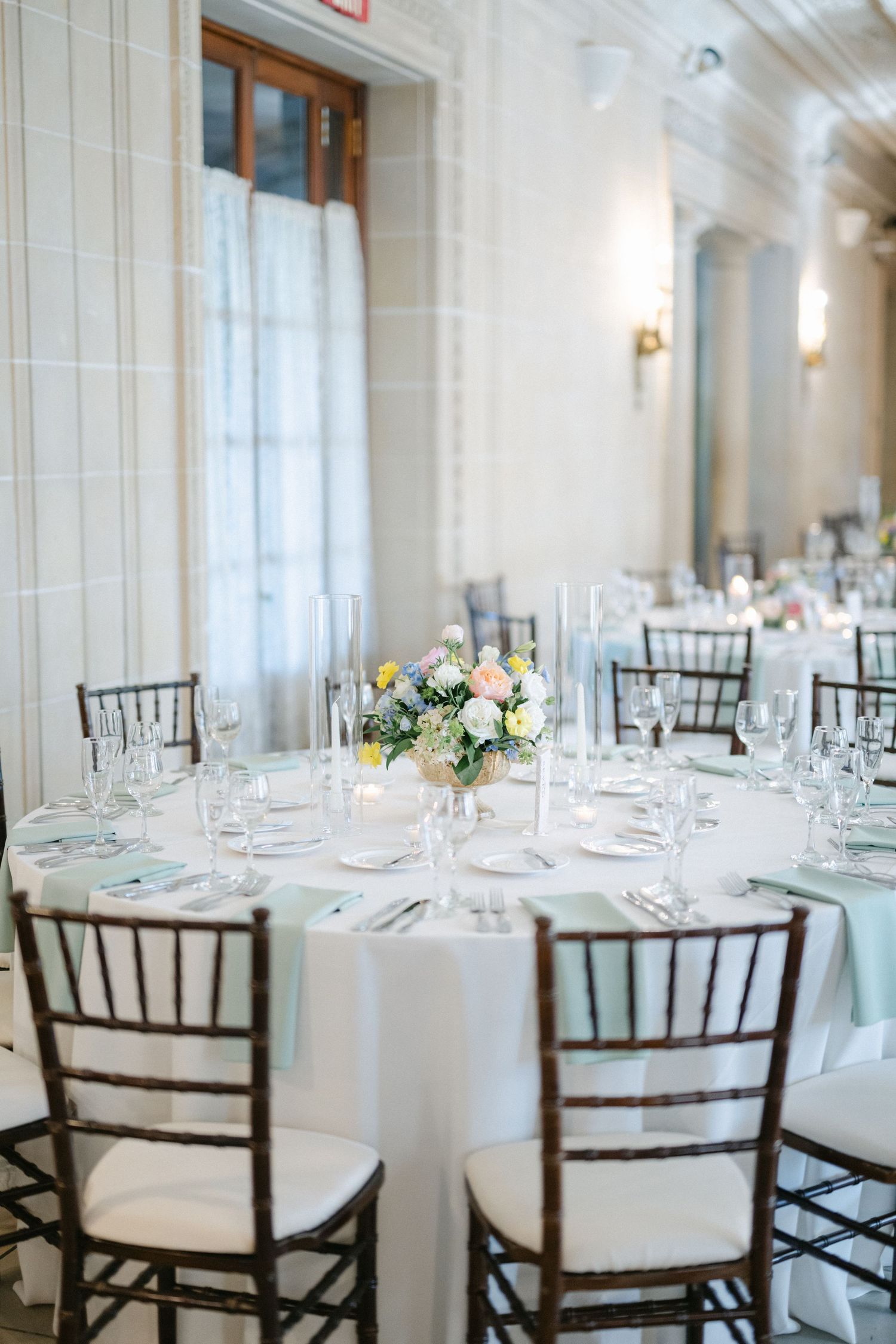 Armour House Wedding - Elegant wedding reception table with white linen, mint napkins, floral centerpiece, and dark wood Chiavari chairs.