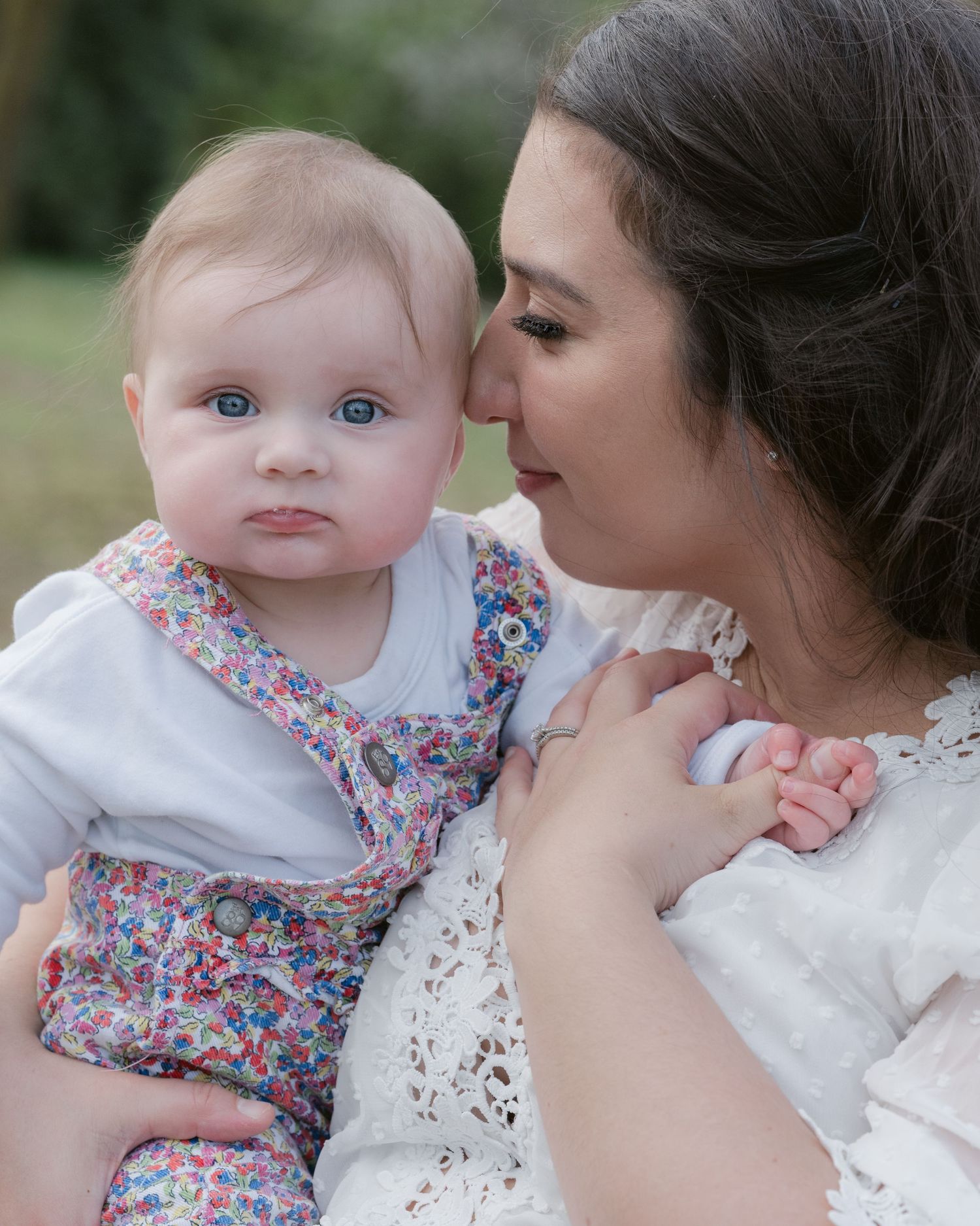 Close-up lifestyle portrait of a mother holding her baby girl during an outdoor spring photoshoot at Jericho Beach Park in Vancouver.