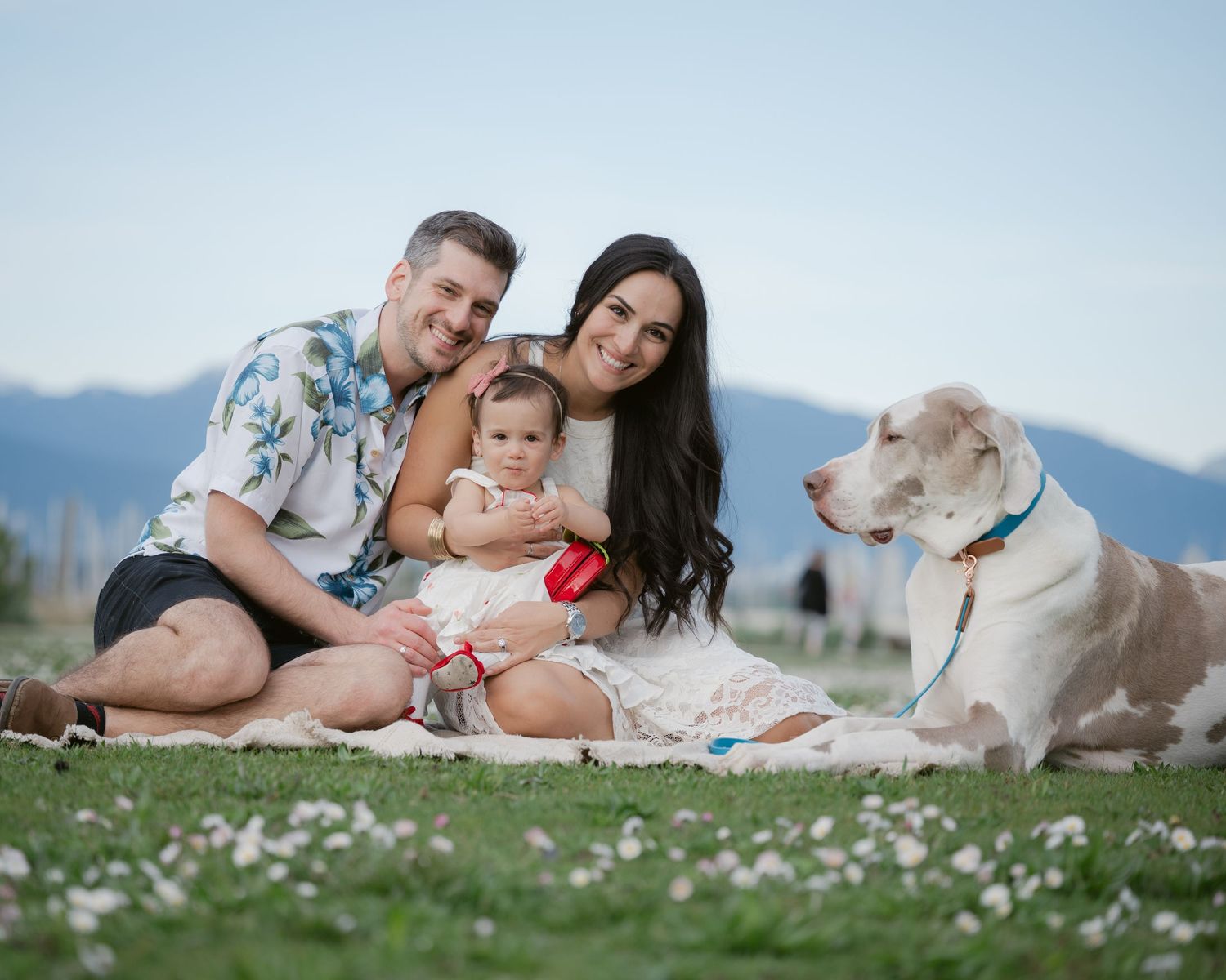 Family of three and their dog on the grass at a Jericho Beach family photo session in Vancouver.