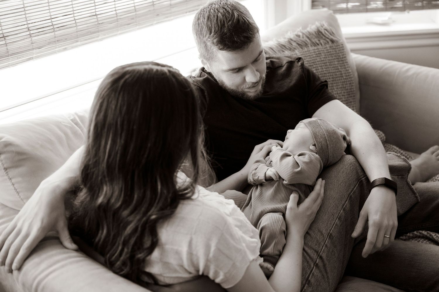 young family with newborn cuddled up on the couch in black and white