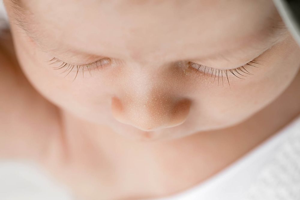 Extreme close-up macro portrait of sleeping newborns delicate facial features and long eyelashes.