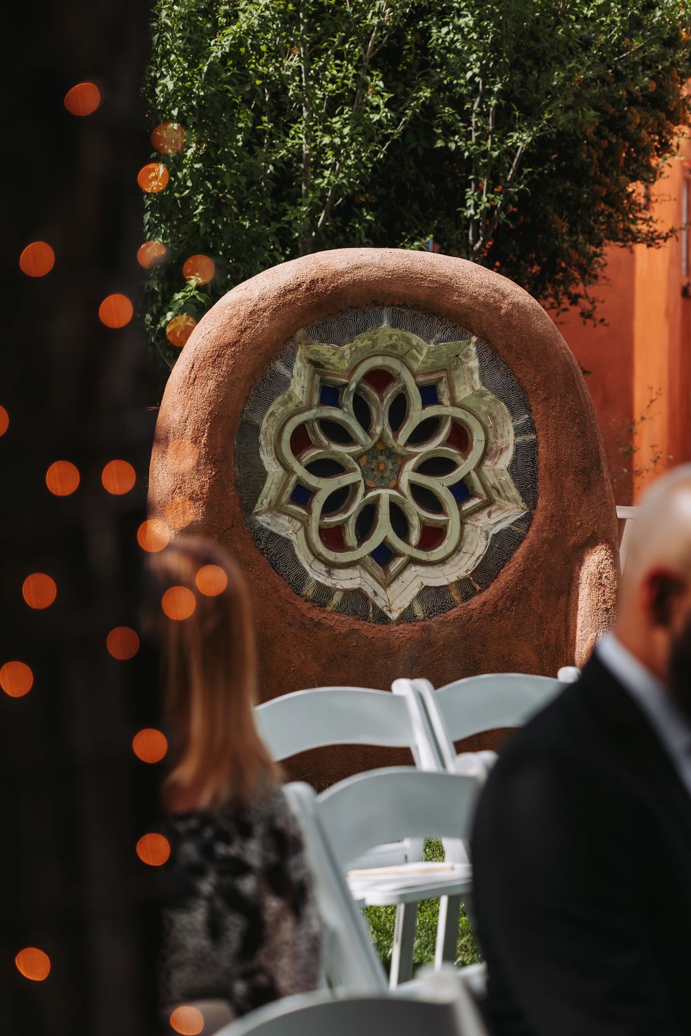 Decorative stone medallion with floral mosaic design at an outdoor wedding venue with warm bokeh lights.