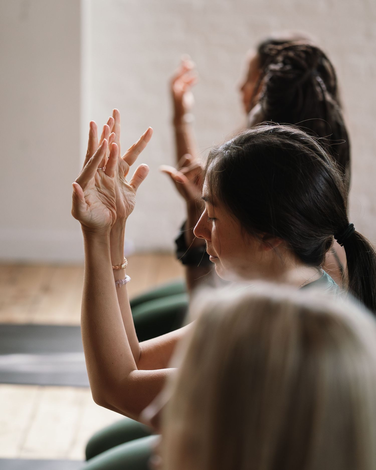 Students raising hands in a classroom setting, engaged in an interactive learning session with natural light.