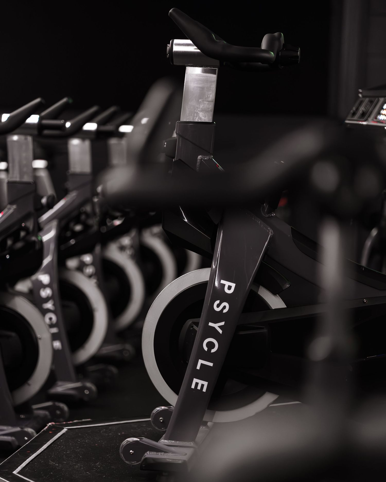 Psycle branded indoor cycling bikes lined up in a dark modern spin studio.