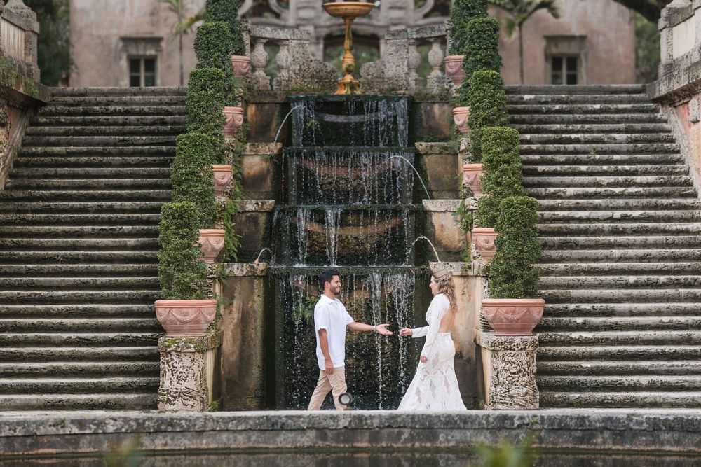 Couple stands in front of Vizcaya’s grand cascading fountain, framed by stone staircases and lush manicured gardens.