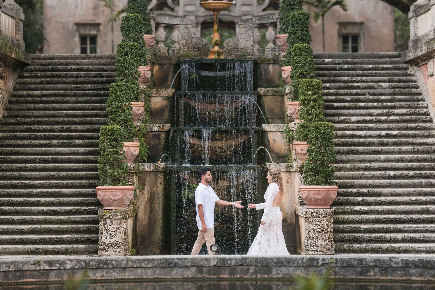 Couple stands in front of Vizcaya’s grand cascading fountain, framed by stone staircases and lush manicured gardens.