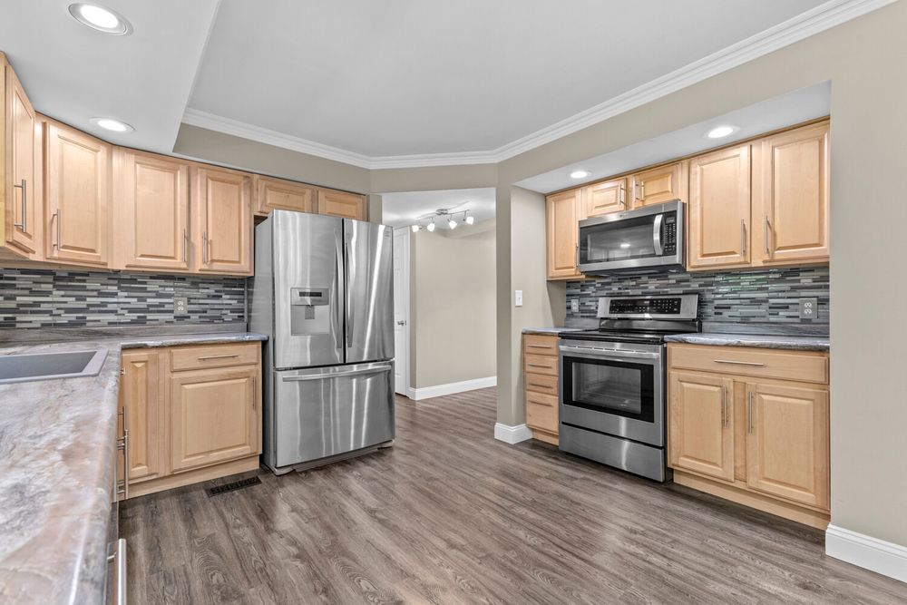 Well-appointed kitchen featuring light wood cabinets, stainless steel appliances, and decorative tile backsplash.