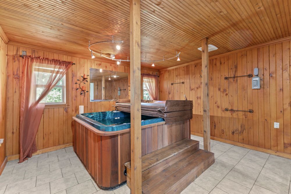 Cozy wood-paneled room featuring a built-in hot tub spa with tile flooring and track lighting.