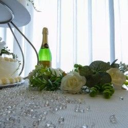 Elegant wedding table with champagne bottle, white roses, and crystal decorations.