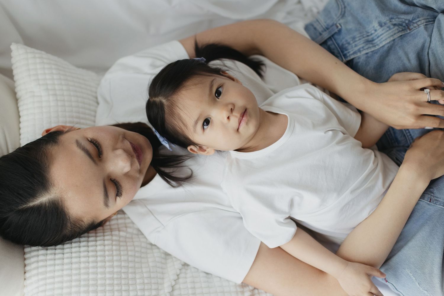 A parent and young child lying together on a bed, sharing a peaceful and loving moment.