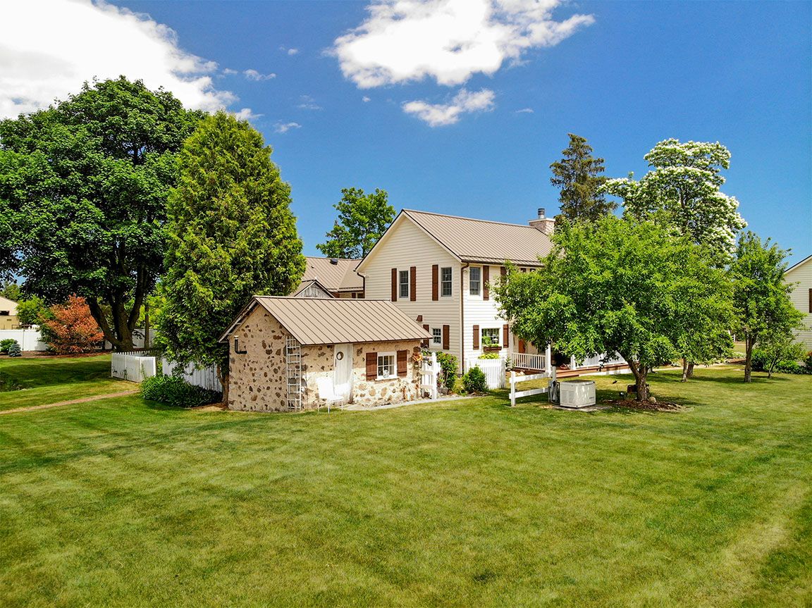 Aerial drone photo of a beige two-story home with large yard, Milwaukee area