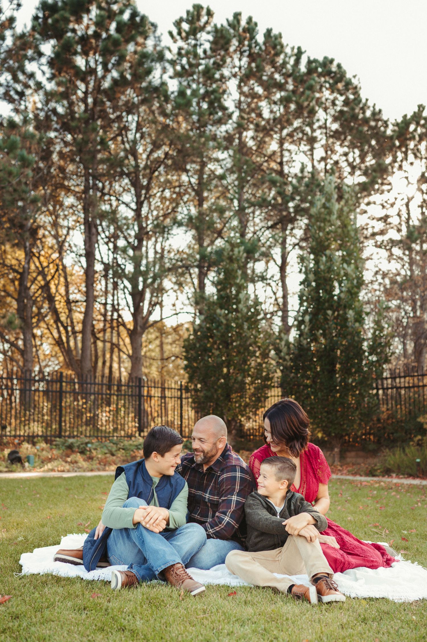 Family photos in a natural outdoor setting with parents and children on a blanket, pine trees and soft golden light.