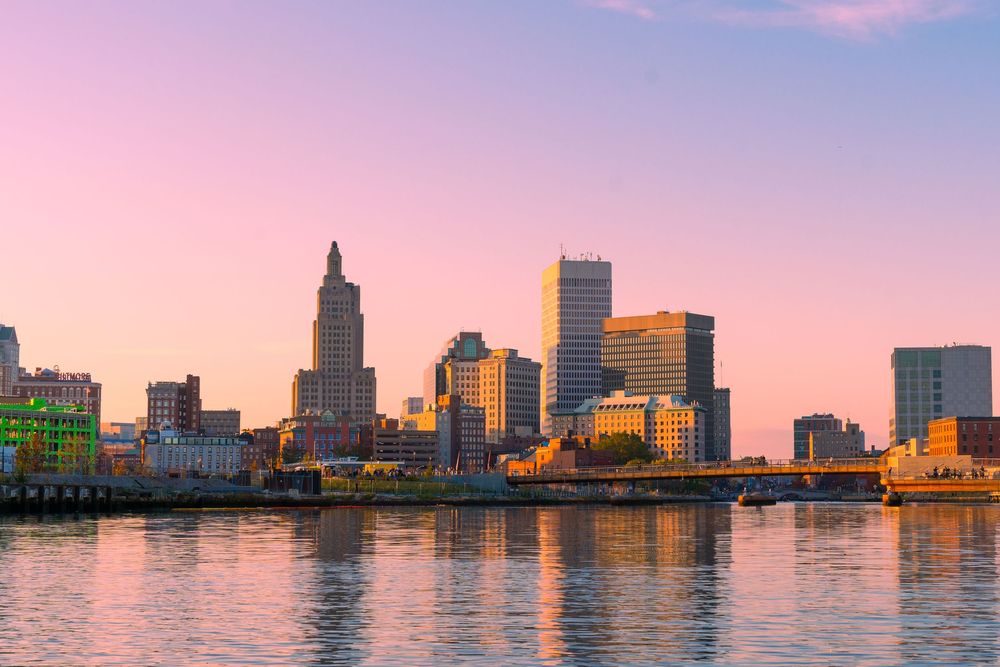 Providence, Rhode Island skyline reflecting on the river at sunset with pink and purple hues in the sky.