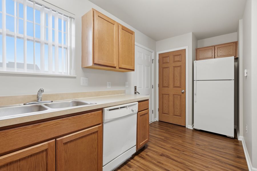 Modern kitchen with oak cabinets, white appliances, double sink, and hardwood floors.