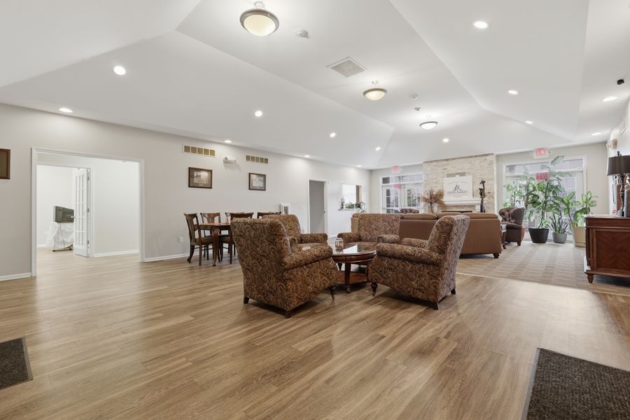 Spacious senior living room with hardwood floors, cozy seating areas, and an open layout leading to a dining area.