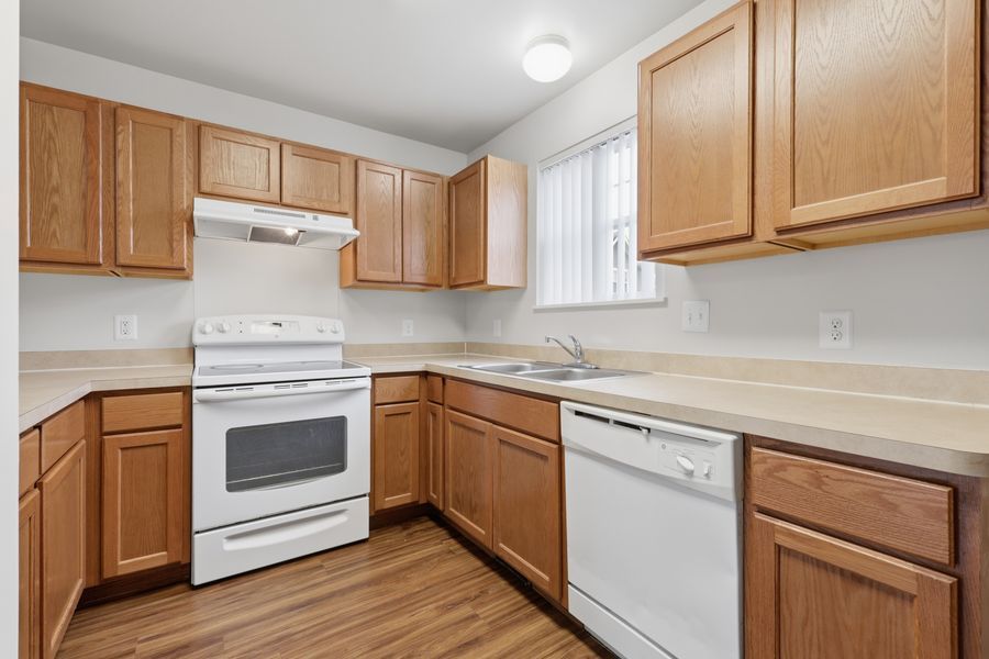 Bright kitchen with oak cabinets, white appliances, laminate countertops, and hardwood floors in a clean layout.