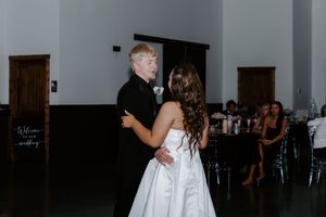 Bride and groom sharing their first dance in an elegant white reception hall.