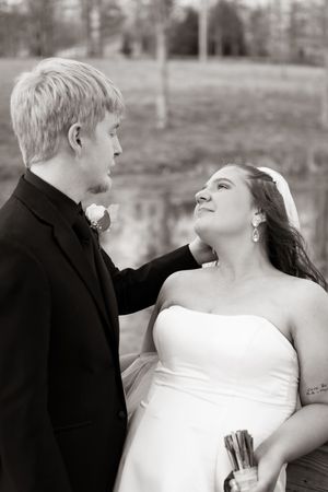 Bride and groom share a romantic moment outdoors in this classic black and white wedding portrait.