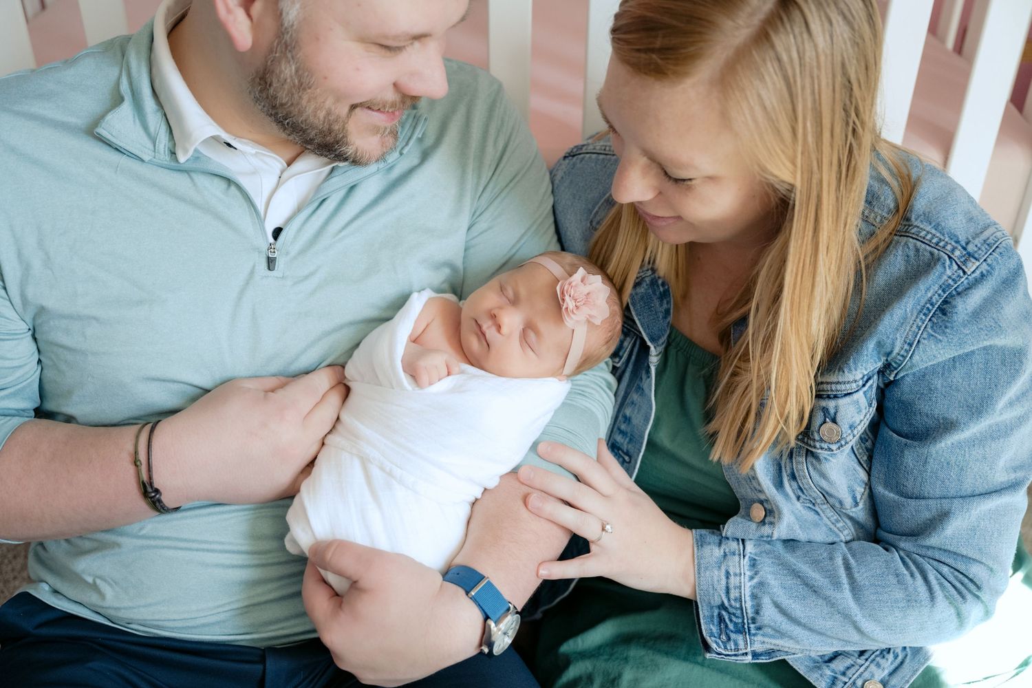 parents holding swaddled and sleeping newborn in nursery during in home lifestyle newborn session in lake elmo, mn